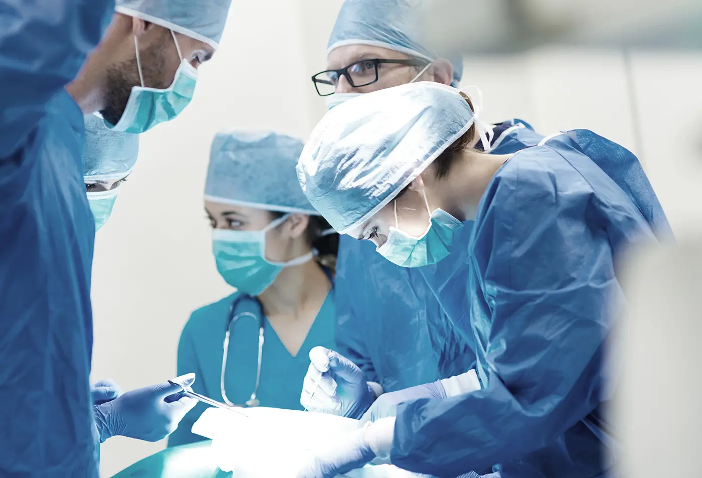 Surgeons and medical staff performing surgery under bright operating lights.